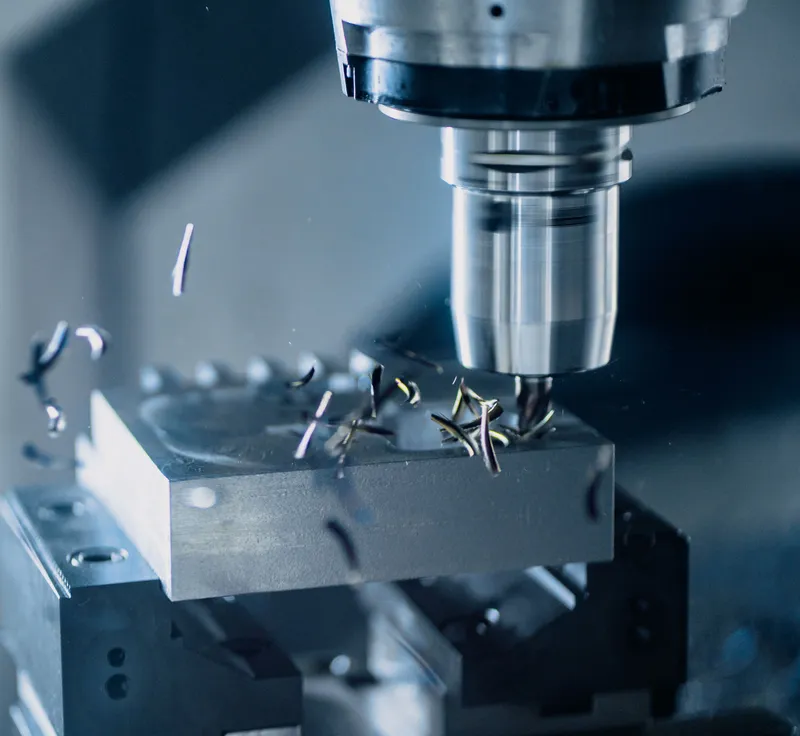 CNC milling tool cutting a steel workpiece with metal chips